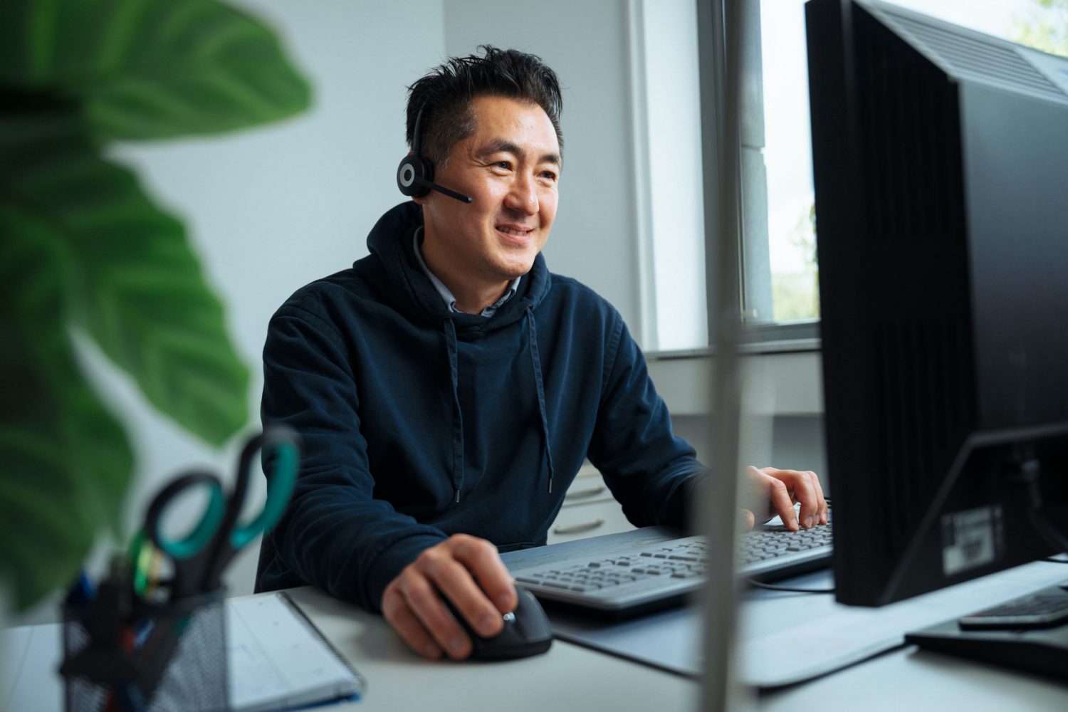 imulani Mitarbeiter mit Headset am Schreibtisch